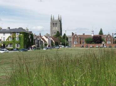 Part of Long Melford village green showing the church and the tudor Trinity Hospital.