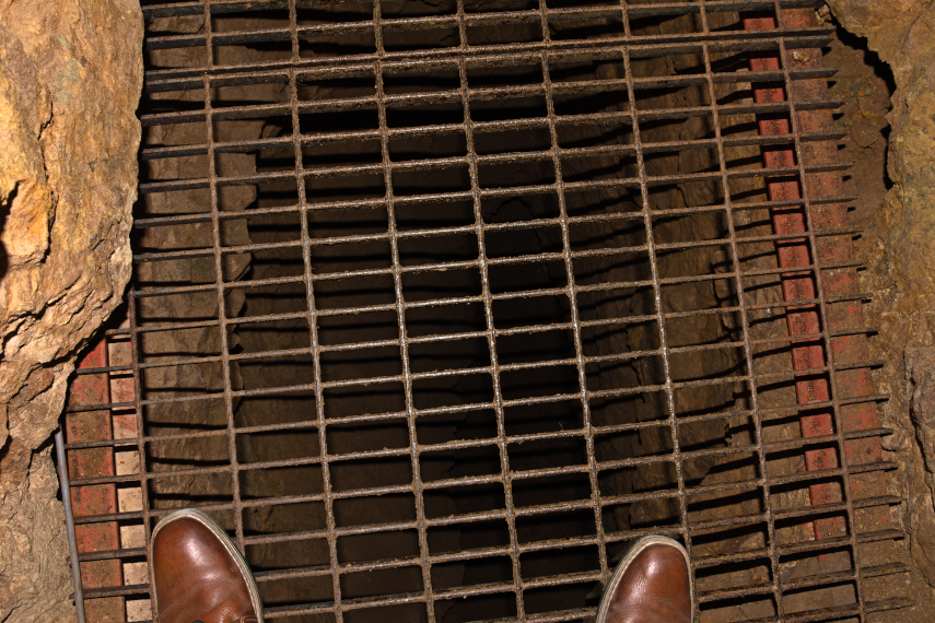 A deep, dark Abyss covered with a grill, Great Orme Mines, Llandudno, Caernarfonshire, Wales, Great Britain