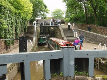 Scene showing two canal narrowboats negotiating a series of three locks on the Shropshire Union Canal, Chester, Cheshire, England